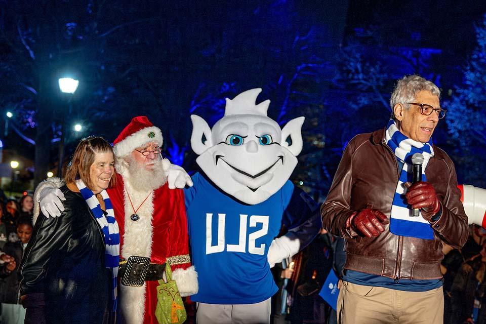 The Billiken, Santa Claus, University President Fred Pestello, Ph.D., and Fran Pestello, Ph.D., stand together at Christmas on the Quad. Photo by Sarah Conroy.